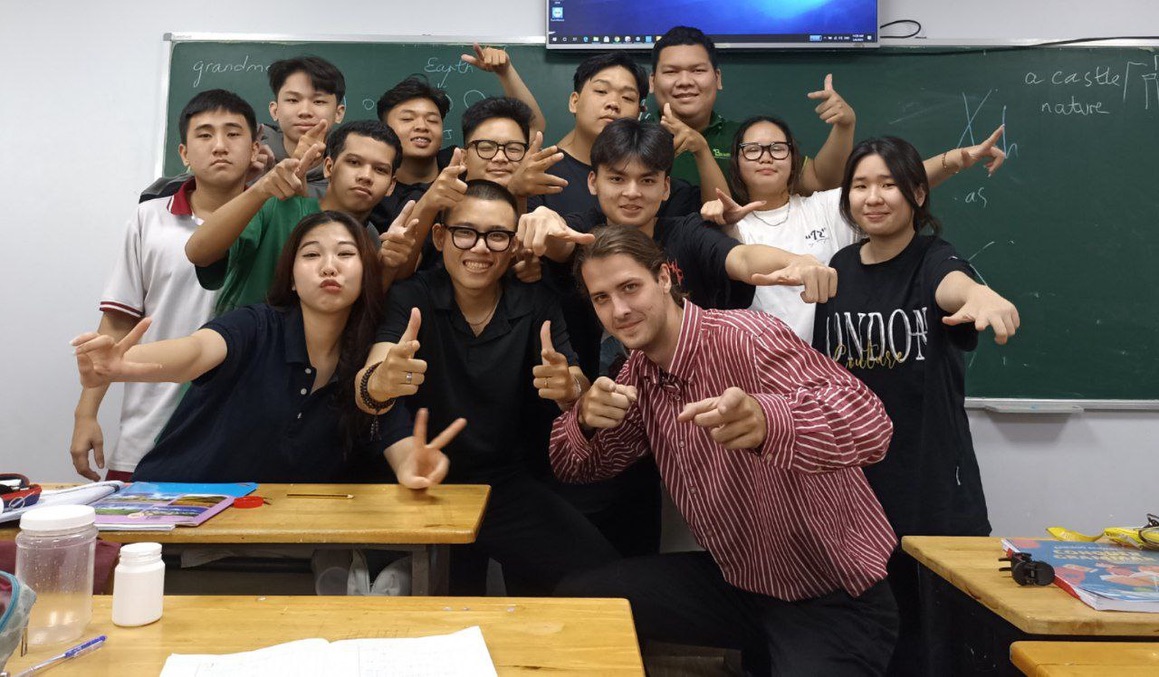 Foreign English teacher posing with Vietnamese teenage students in classroom Vietnam