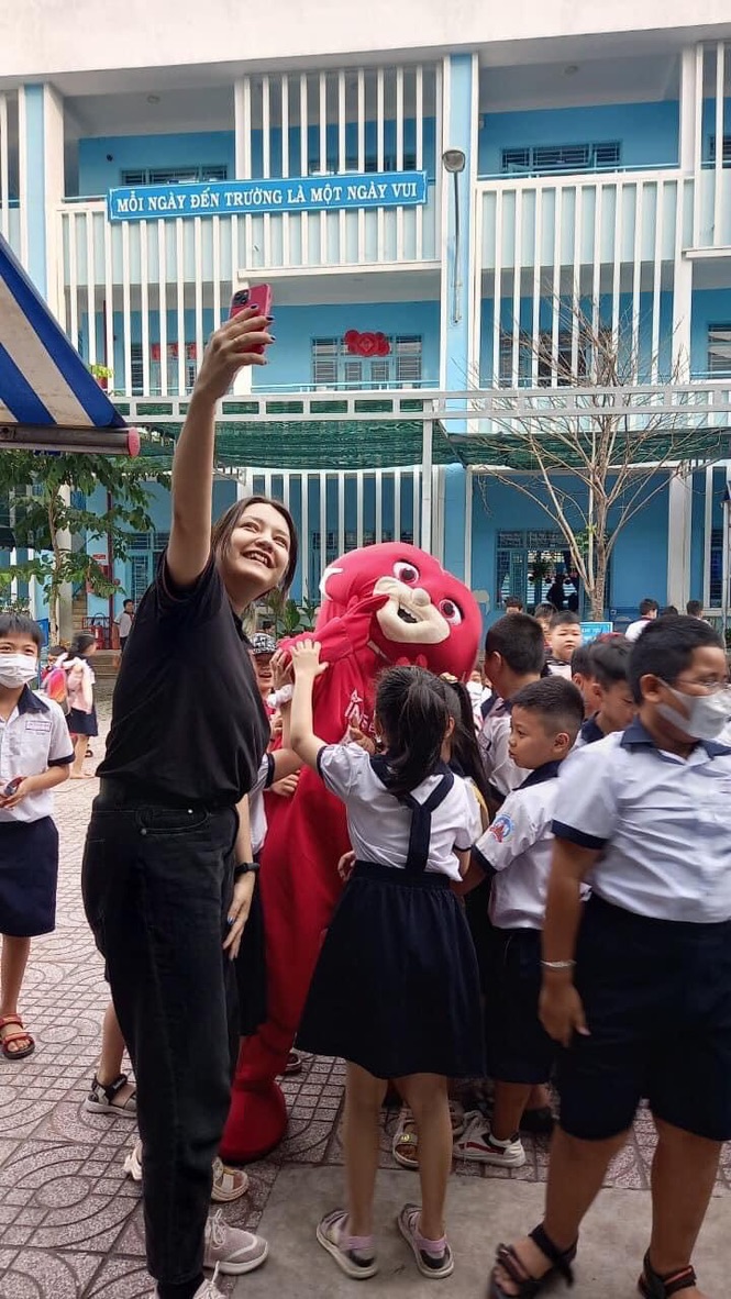Female English teacher taking selfie with school mascot and students at Vietnamese school event