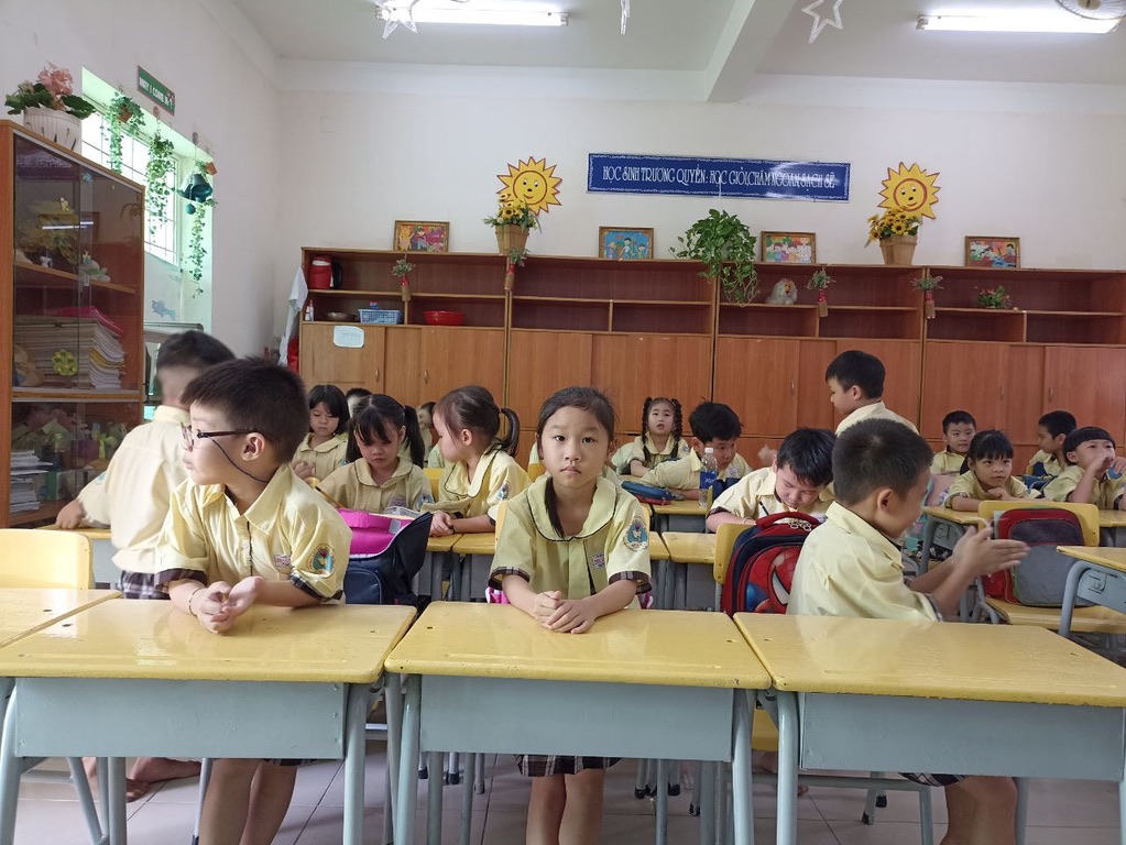 Vietnamese primary school students in yellow uniforms sitting at desks classroom