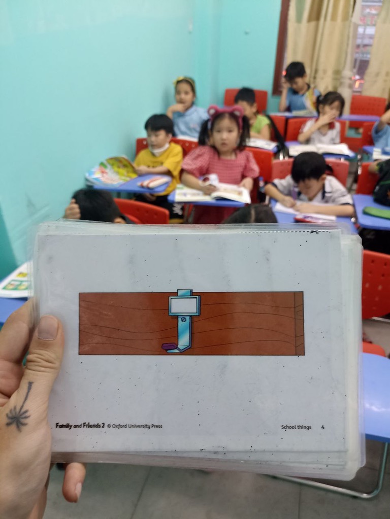 Teacher holding Oxford University Press flashcard with Vietnamese students studying in background