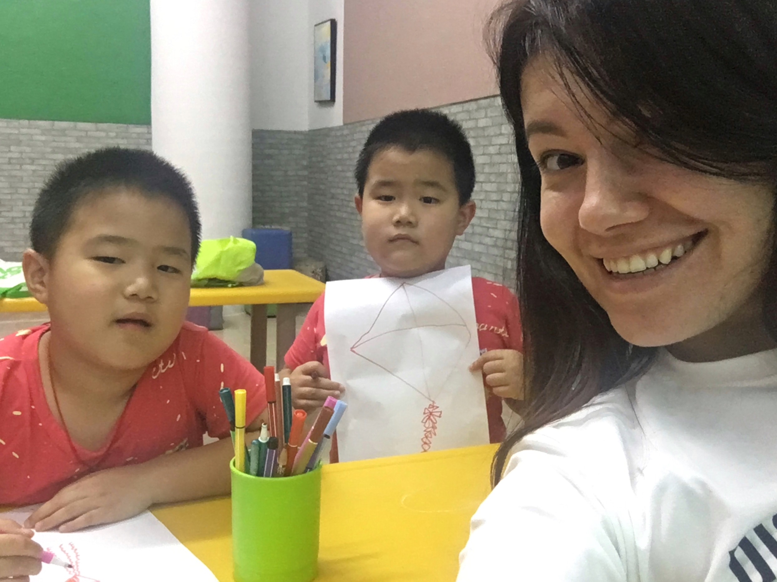 Female non-native English teacher doing craft activities with young students Vietnam