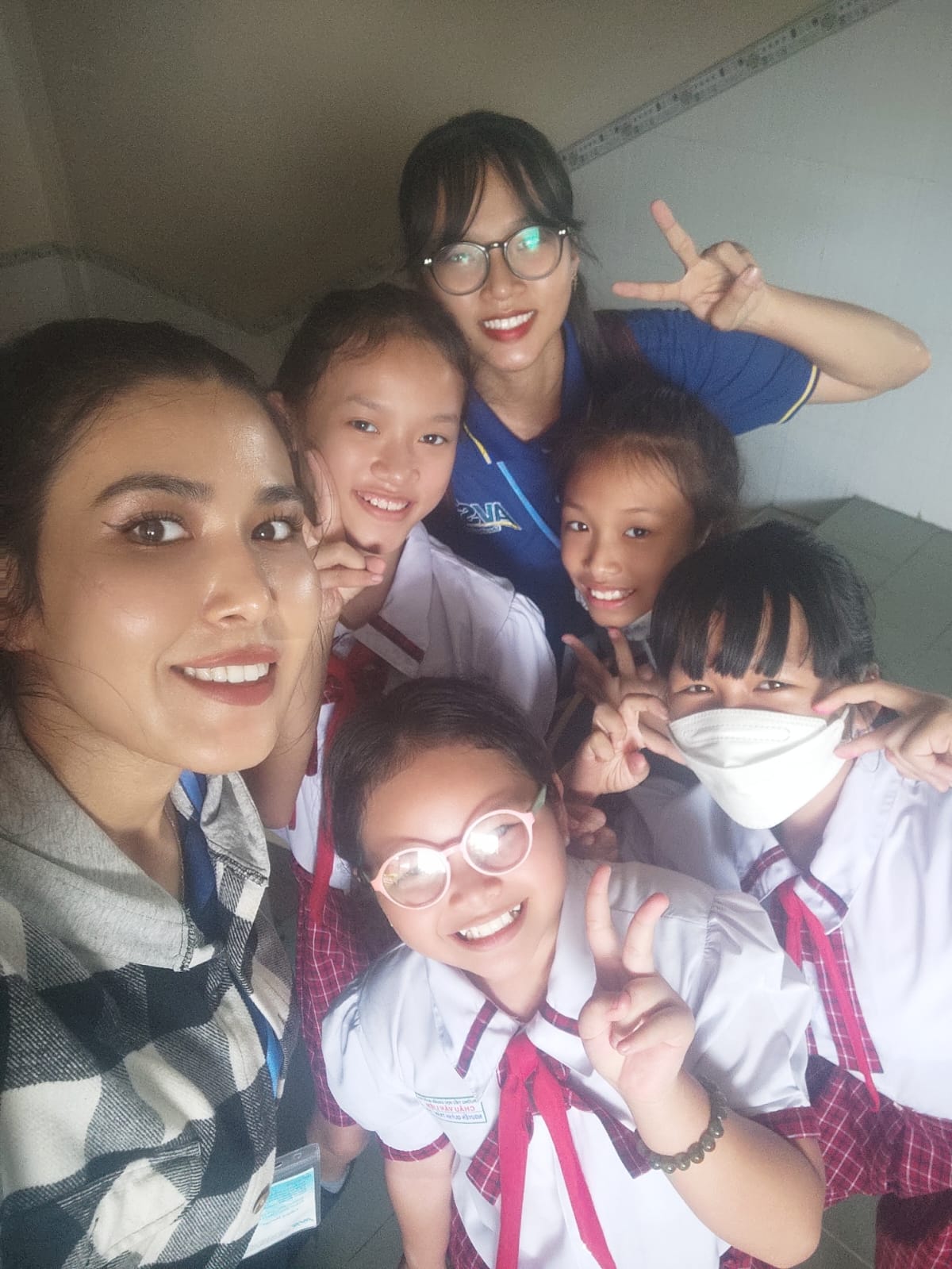 Female non-native teacher selfie with Vietnamese students in school uniforms